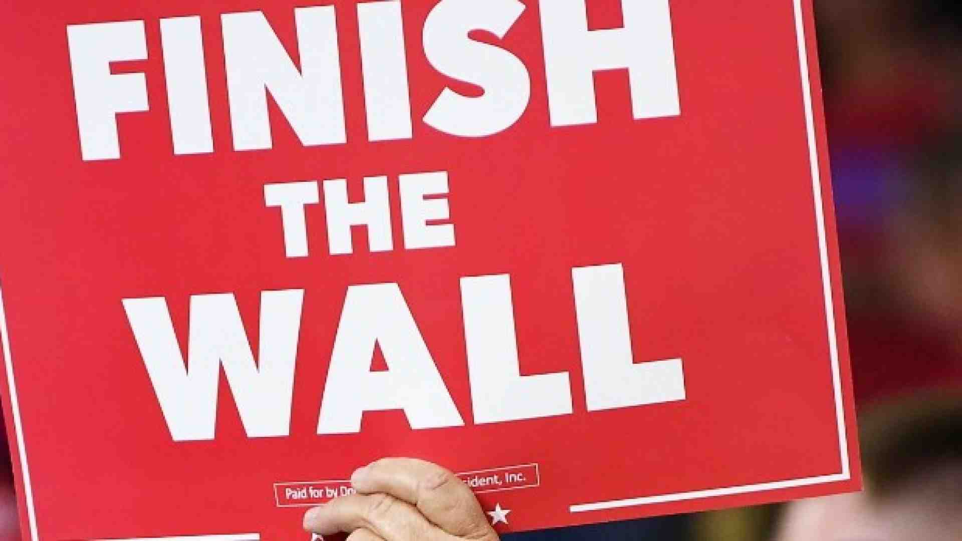 Un sostenitore di Trump espone il manifesto: "Costruite il muro" (Foto LaPresse)