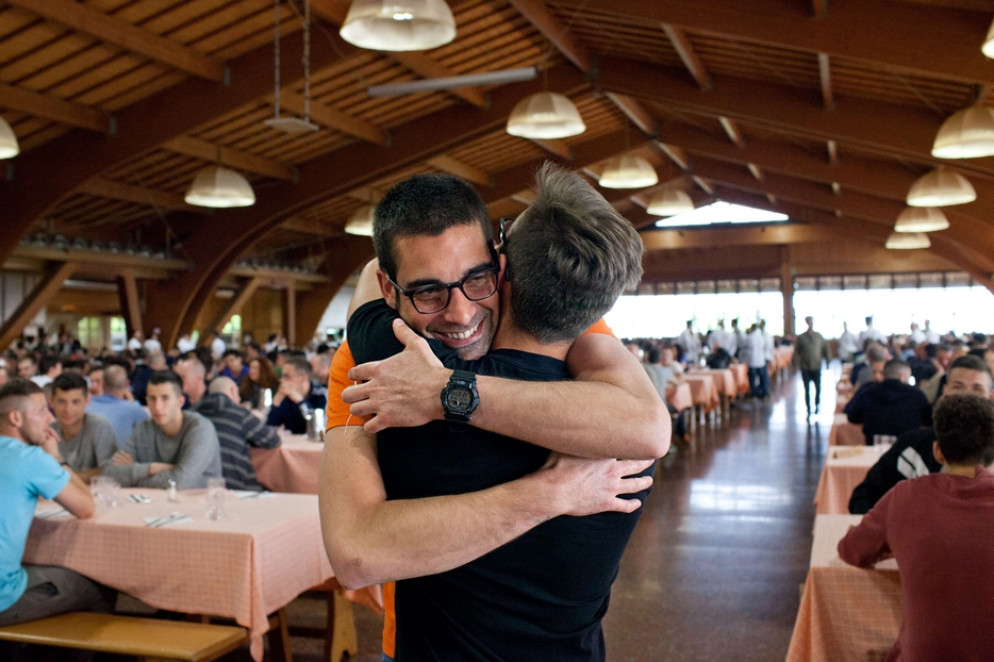 Un abbraccio, prima dell'avvento del Covid, tra due ragazzi nel grande salone della comunità riminese di San Patrignano