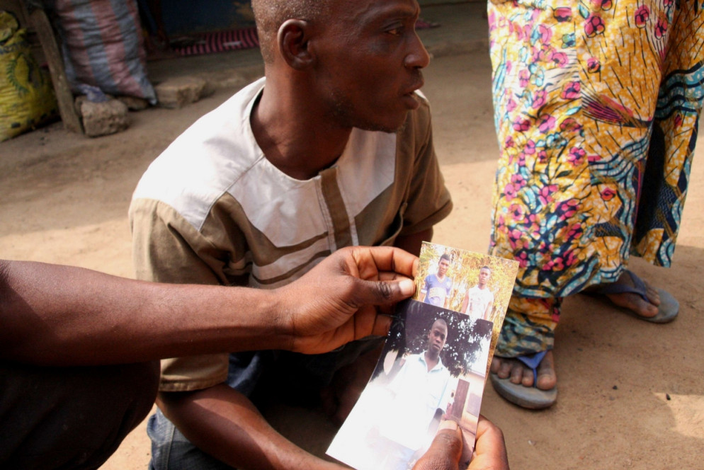 Il fratello poliomelitico di Tamimou Derman con le foto di qualche anno prima del migrante morto e un altro fratello (foto M. Fraschini Koffi)