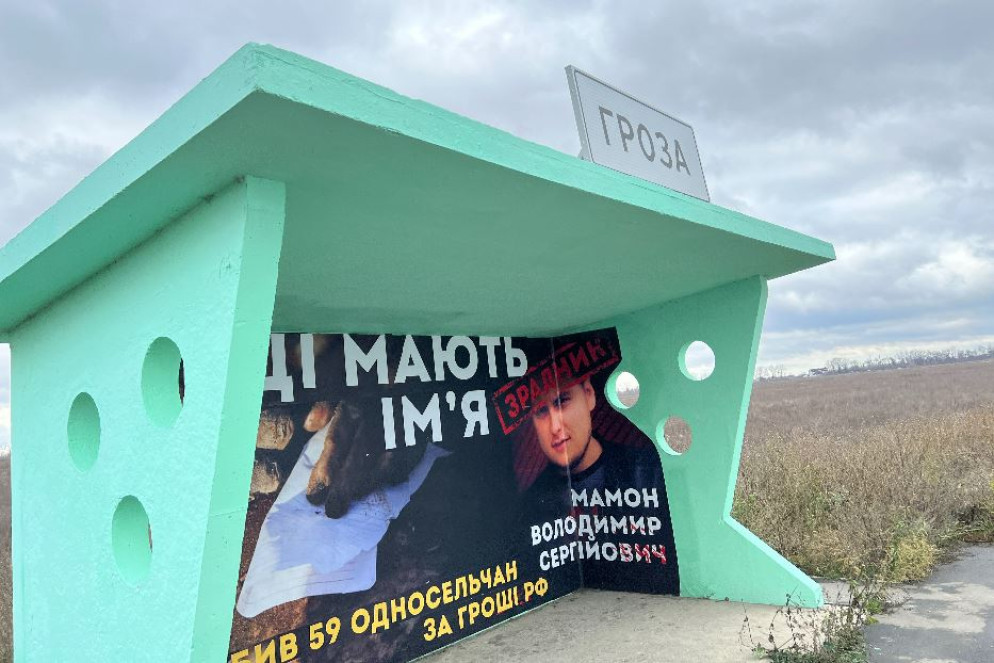 La fermata del bus a Groza con il manifesto che indica il nome del "traditore": è accusato di aver aiutato i russi a pianificare la strage al bar - Gambassi