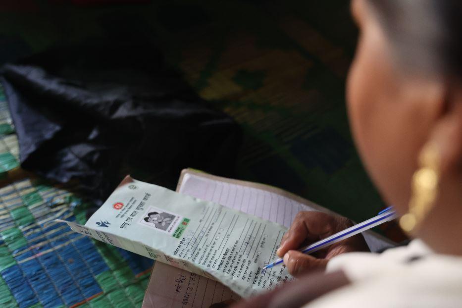 An ASHA fills out the Mother and Child Protection (MCP) card during routine check-ups to track the child’s growth, vaccinations, and overall health - Khabar Lahariya